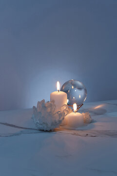 Crystals, glass ball and candles on marble background