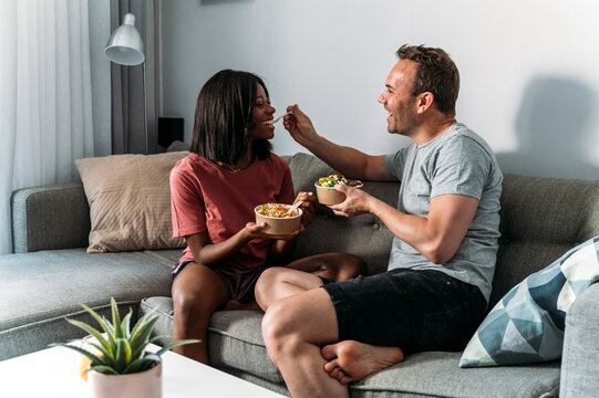 Content diverse couple eating poke bowls at home