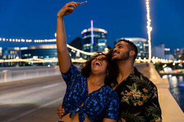 Young Black couple taking selfie photo with mobile phone in city night