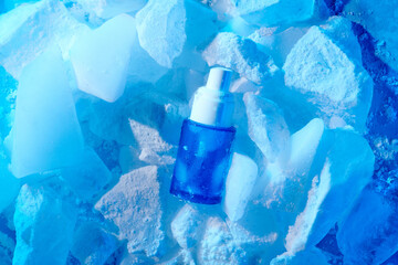 Skincare serum essence glass bottle on ice blue background