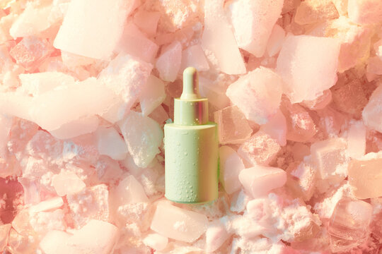 Bottle of cosmetic product and ice cubes in frozen on color background