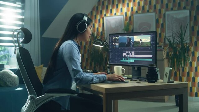 Asiman female freelancer in headset editing travel blog video to customer on moderm pc during remote work at home office