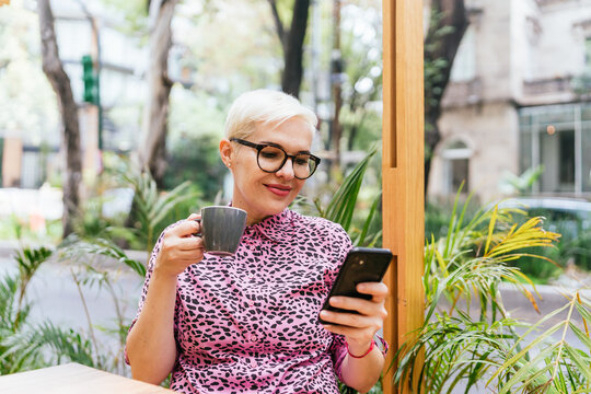 Woman Looking At Phone And Drinking Coffee