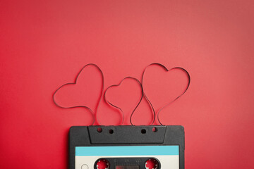 Music cassette and hearts made with tape on red background, top view. Listening love song