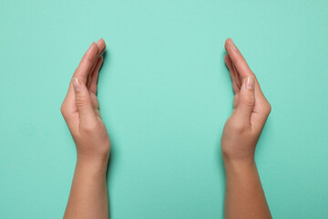 Woman holding on turquoise background, closeup of hands. Space for text