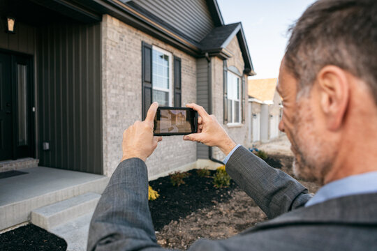Real Estate Agent Photographs Home With Phone