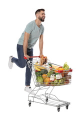 Happy man with shopping cart full of groceries on white background