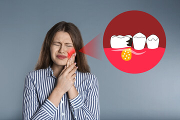Young woman suffering from acute toothache on grey background