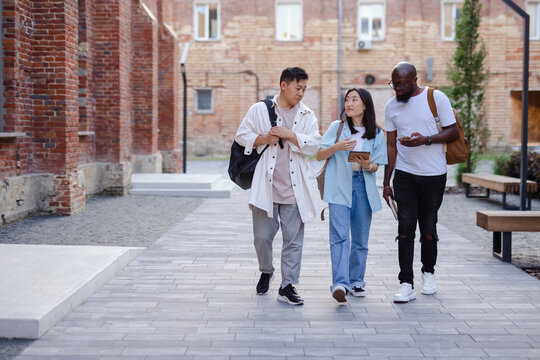 Friends with gadgets strolling in campus 