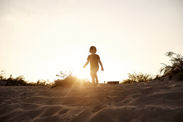 silhouette of a little boy running in a sandy land