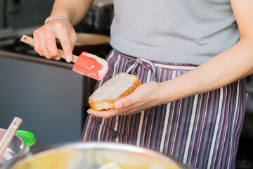 Hands of an unrecognizable person placing mayonnaise on a loaf of bread.