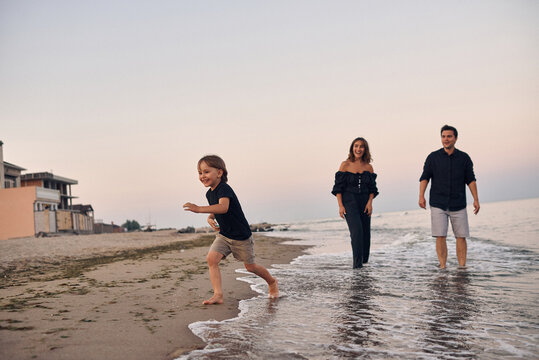 a young family runs along the seashore
