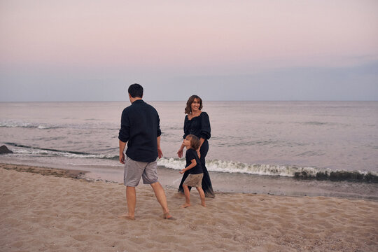 a young family runs along the seashore