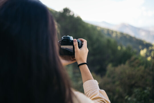 Unrecognizable woman photographing a mountain landscape with camera