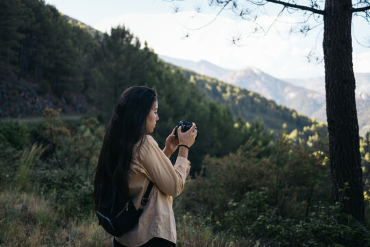 woman photographing a mountain landscape with camera