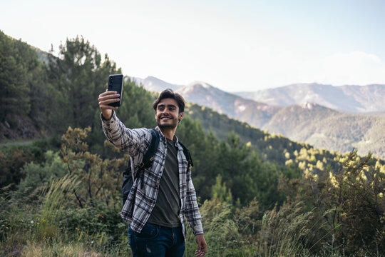 Young man taking a selfie in a beautiful mountain landscape