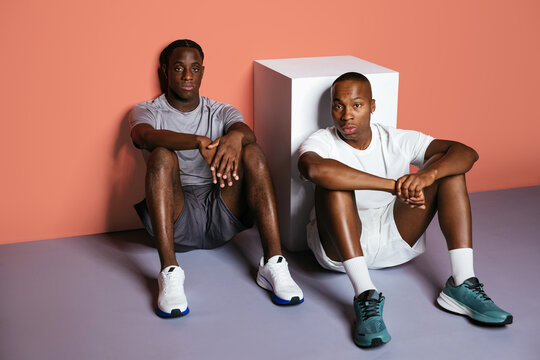 Black sportsmen sitting near cube in studio