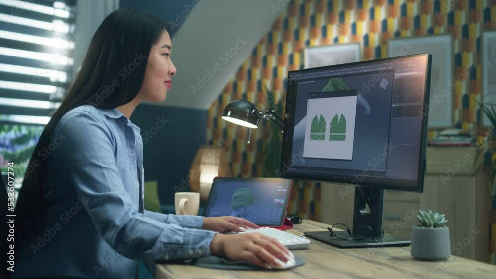 Poster asian woman creating 3d models of clothes on computer and tablet in 3d modeling program, while sitti