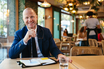 Positive businessman sitting at restaurant table