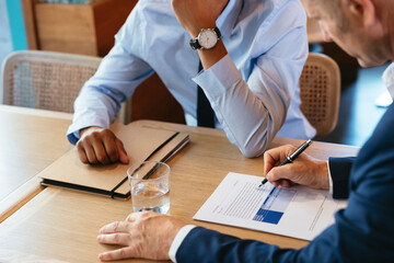 Crop businessmen signing contract during meeting