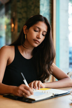 South Asian woman making notes in planner