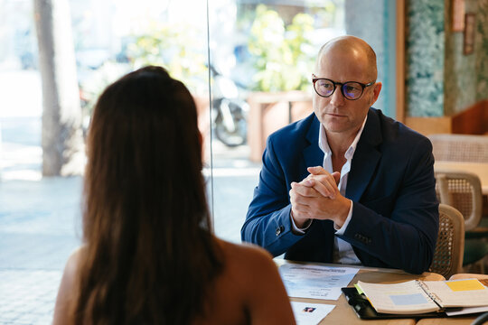 Bald businessman interviewing employee in restaurant