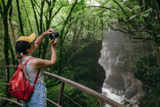 a tourist girl takes pictures of beautiful nature with greenery