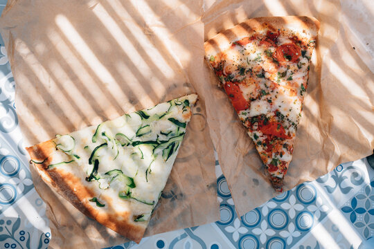 Two slices of pizza under partial shade.