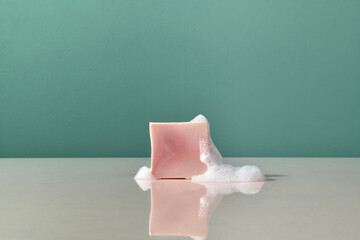 Piece of pink soap and foam on a reflective surface