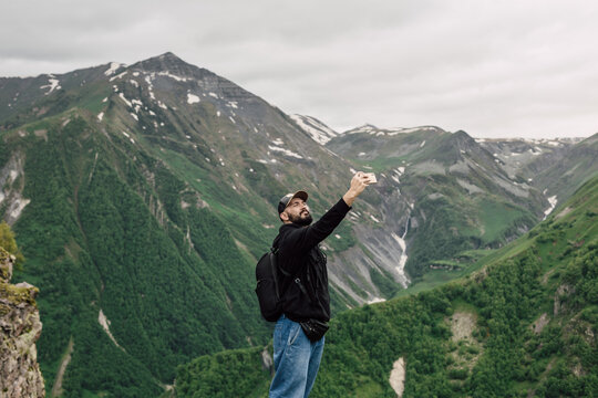 A male tourist takes a selfie with a beautiful mountain view