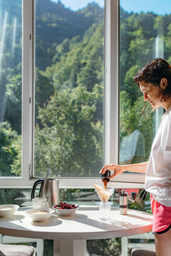 A girl makes coffee with a beautiful view from the window