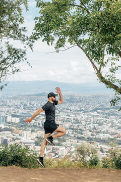 A man in sports clothes does exercises with a view of downtown