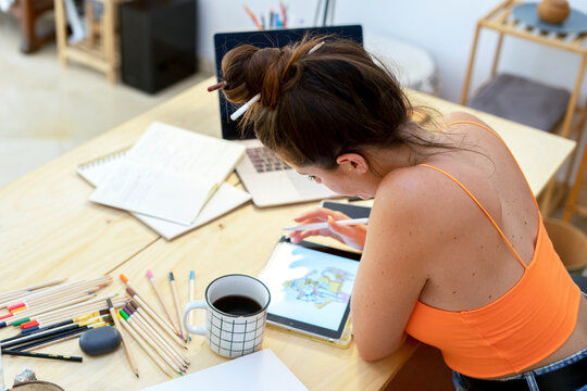 Female illustrator drawing on tablet at desk 