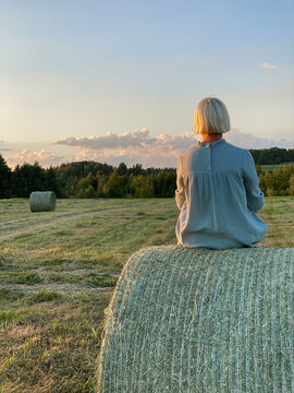 A girl on a haystack in a field.