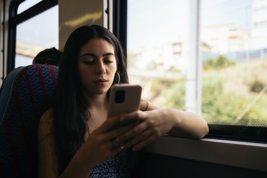 Young woman using smartphone traveling by train