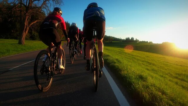 Cyclists team ride bicycles in sunset lights