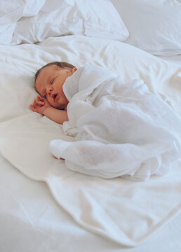 Infant Sleeping Under White Bedspread.