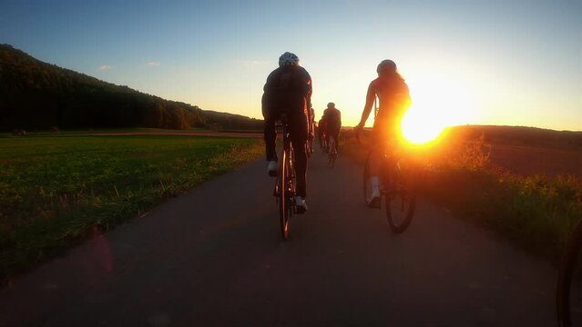 Silhouette of cyclists riding bicycles at sunset