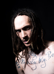 Confident attractive man with serious face. Tattooed hipster on black studio.