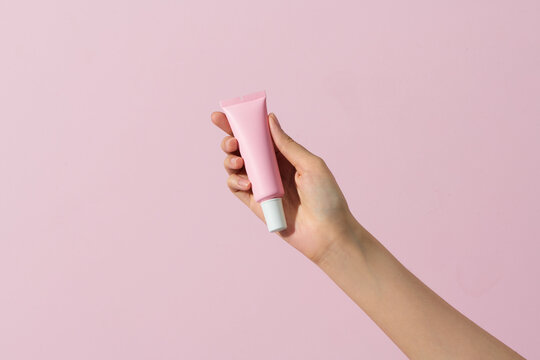 Female hand with squeeze bottle plastic tube container of sunscreen