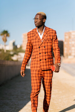 Self assured black guy in stylish suit walking in city