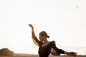 Girl in patterned shirt keeping hands in dance pose