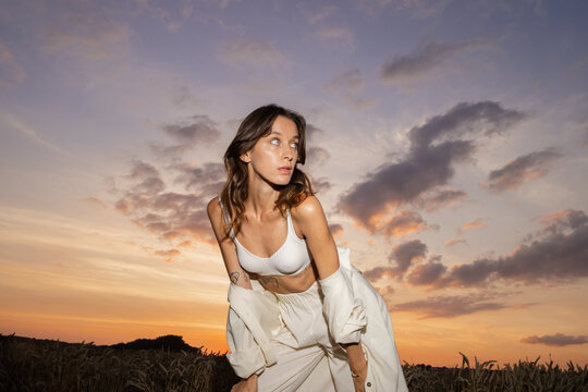 Woman in casual garment posing on empty field 