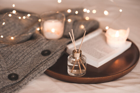 Liquid Home Fragrance In Glass Bottle With Sticks, Open Paper Book, Burning Scented Candles