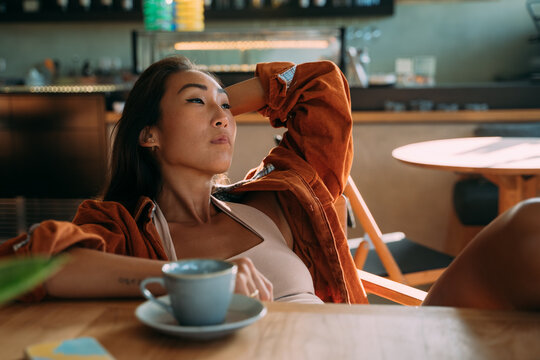 Asian woman relaxing alone at cafe with cup of tea