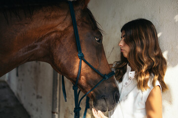 Woman petting her horse in a stable