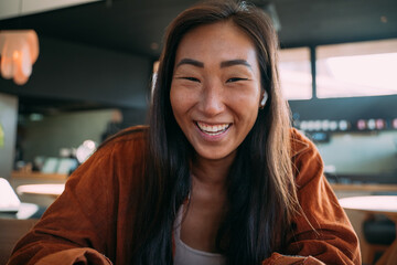 POV, casual woman with ear buds smiling at viewer