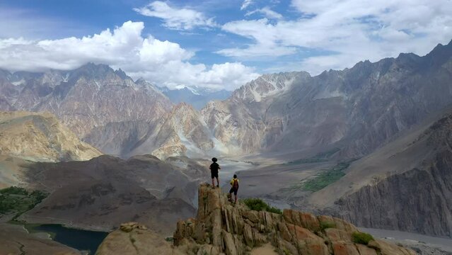 Drone shot of passing over two hikers on peak at Passu Cones  Pakistan, cinematic wide aerial shot