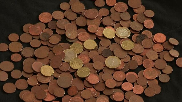 Several coins spread over black cloth, 1 euro coins and many others 20, 10, 5, 2, 1 cent