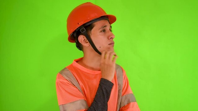 Joven hombre constructor con uniforme y casco en un fondo verde 